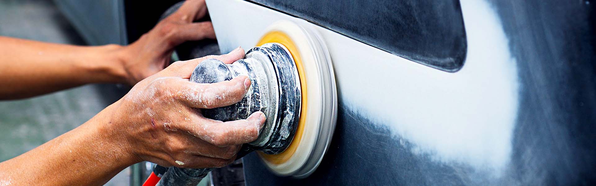 A vehicle body panel being carefully sanded before refinishing